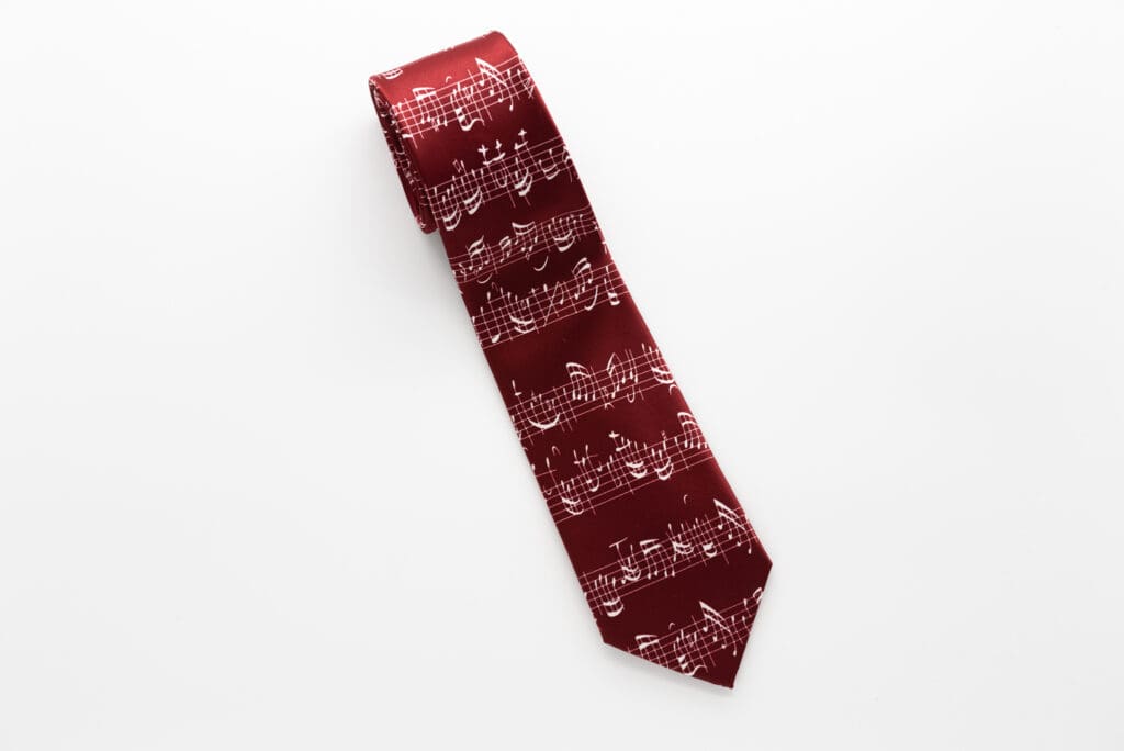 Bordeauxrote Krawatte mit weißem Aufdruck einer mehrzeiligen handgeschriebenen Musikpartitur.