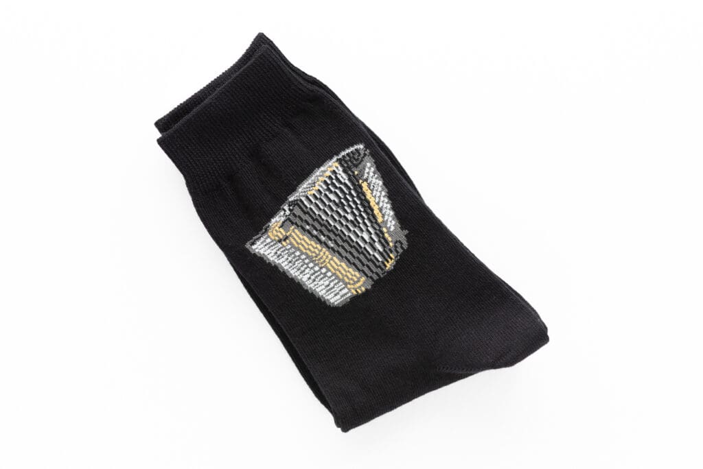 Schwarze Socke mit einem gestrickten gelb-goldenen Akkordeon-Motiv.