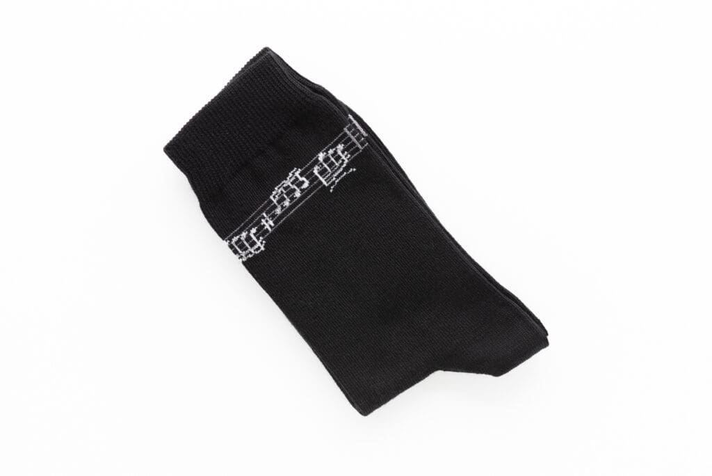 Schwarze Socke mit einem gestrickten weißen Notenzeilen-Motiv.