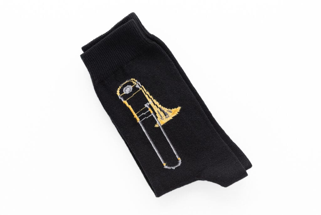 Schwarze Socke mit einem gestrickten gold- und silberfarbenen Posaunen-Motiv.