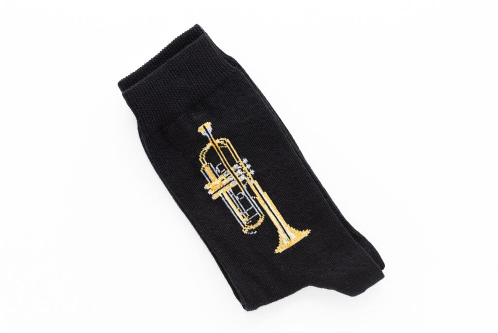 Schwarze Socke mit einem gestrickten gelb-goldenen Trompeten-Motiv.